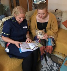 Image of a member of the team from the Teenage Cancer Trust sat with a patient